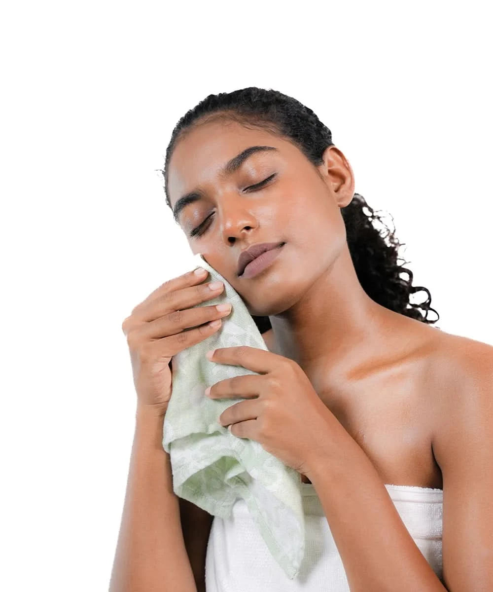 Woman drying her face with a towel on a white background